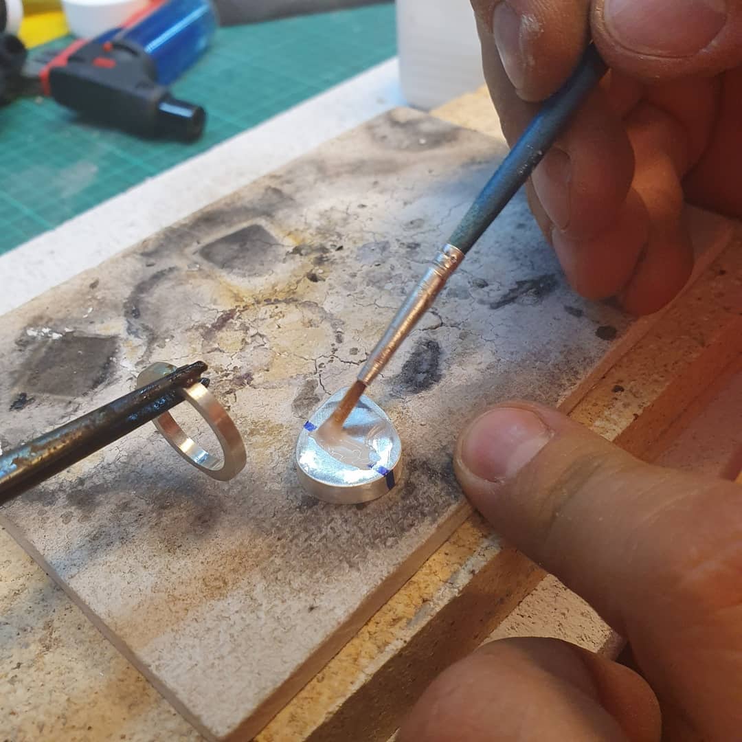 Jewelry soldering setup with torch and silver workpiece on a soldering bench
