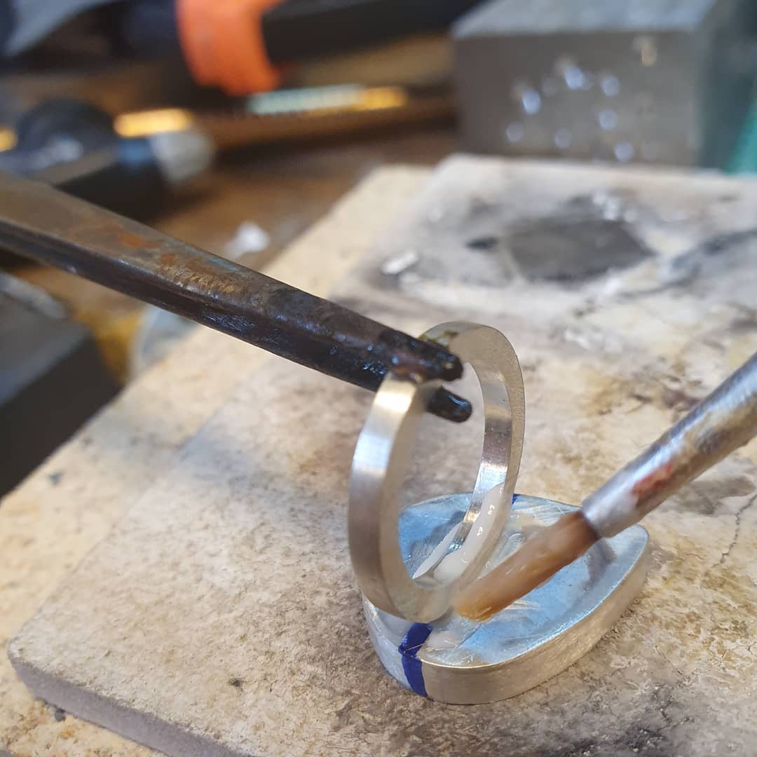 Silver jewelry soldering bench setup showing torch work and heat-safe surface