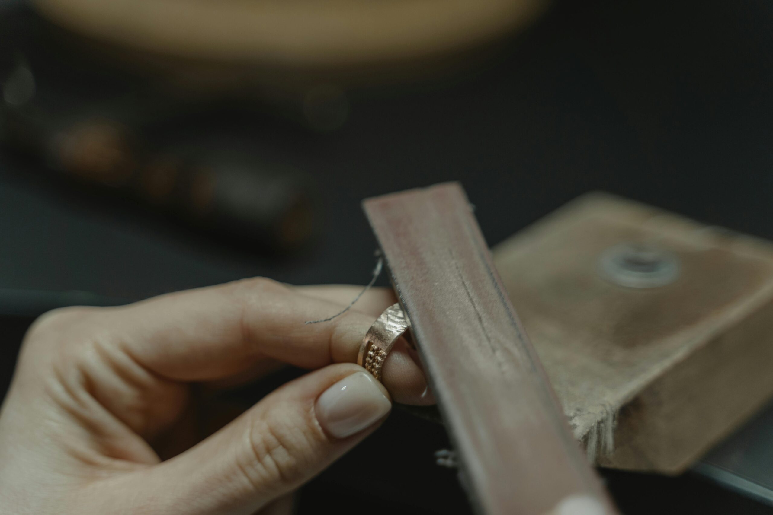 Jewelry maker filing, sanding or polishing a silver jewelry component on the bench