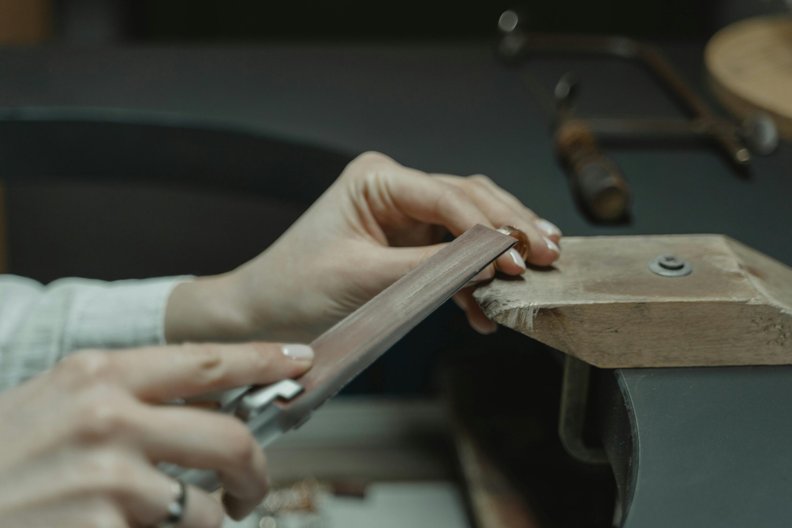 Jewelry maker filing and refining a small silver jewelry component at the bench