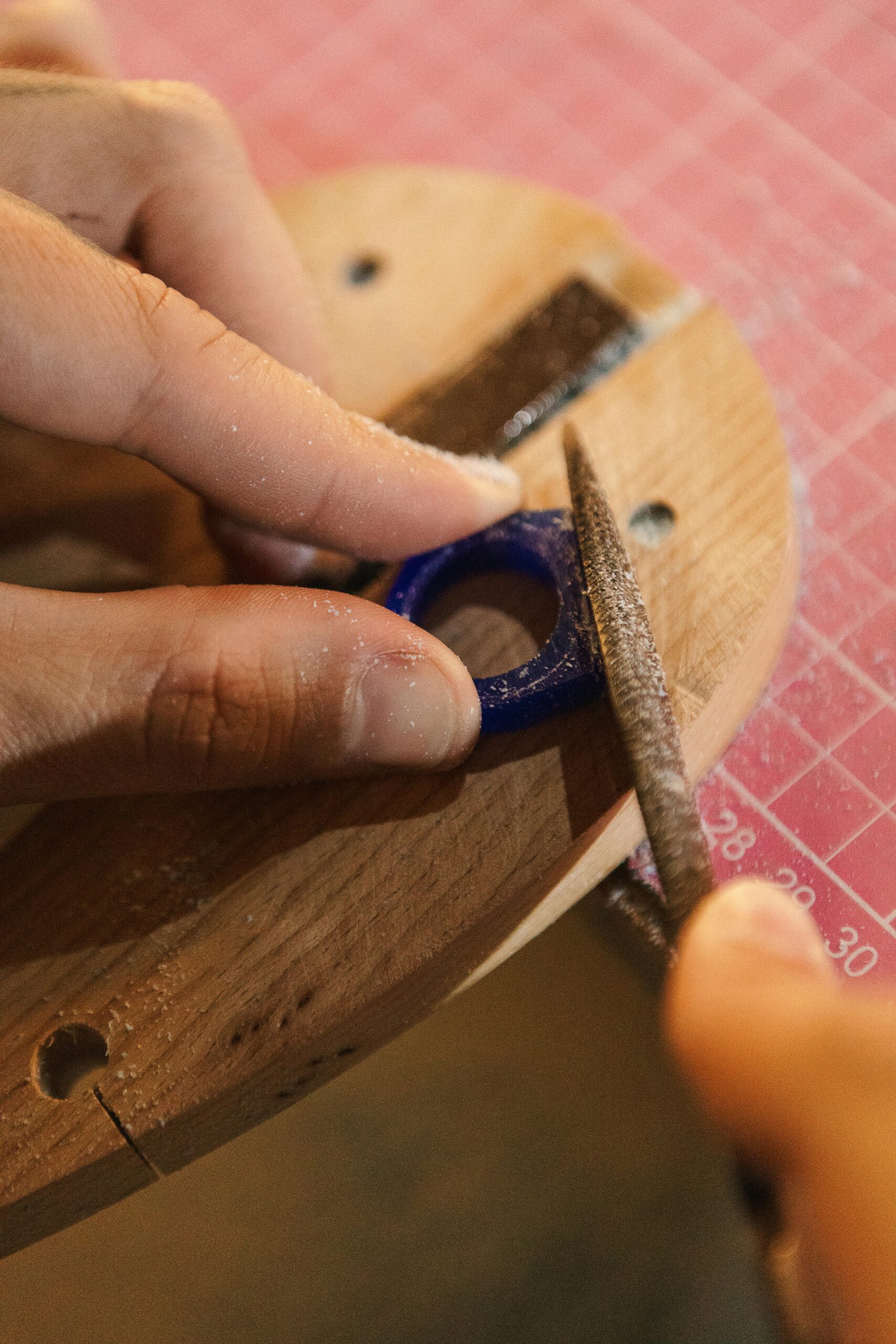 Jewelry maker inspecting and refining a small metal component during filing and finishing