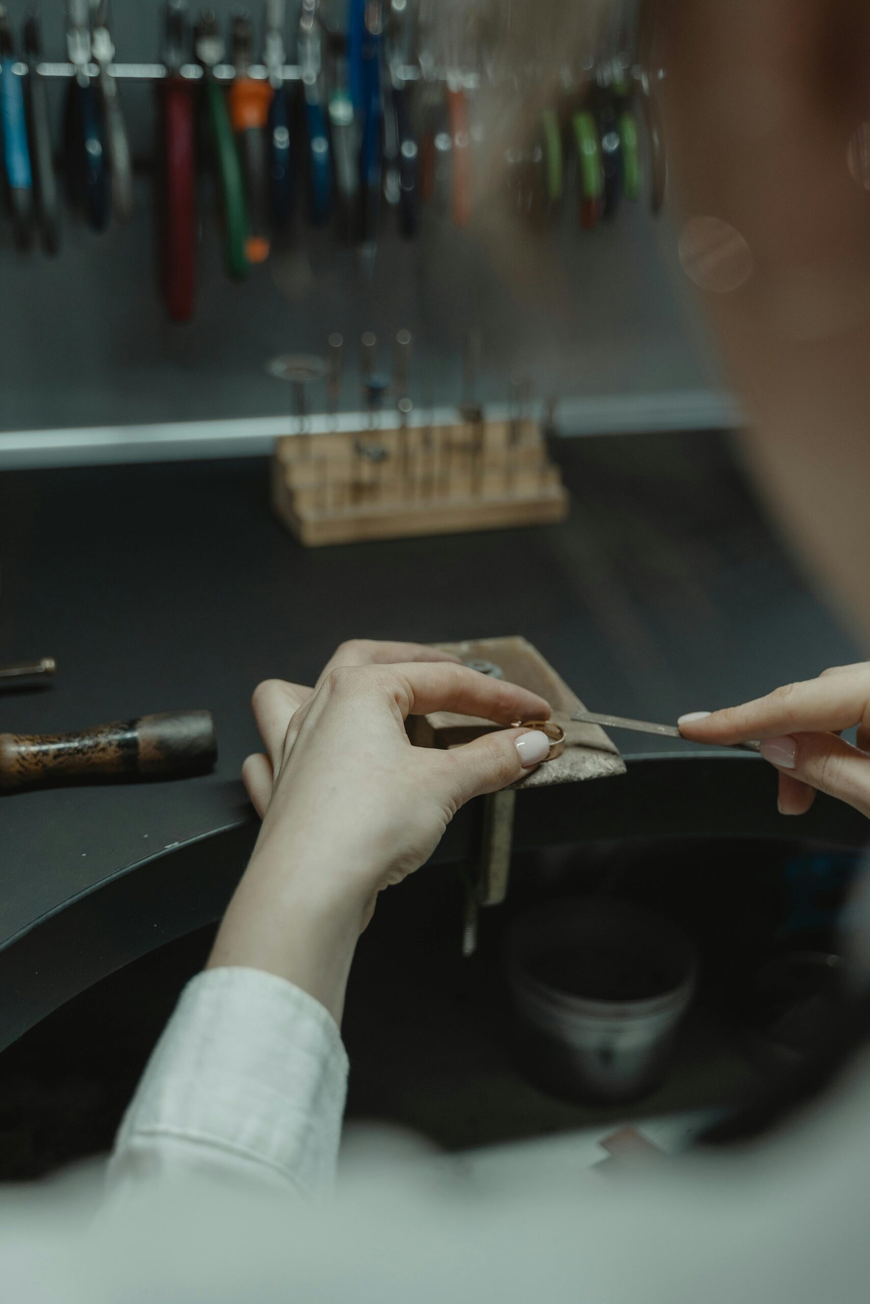 Jewelry maker filing, sanding or polishing a silver component during surface refinement
