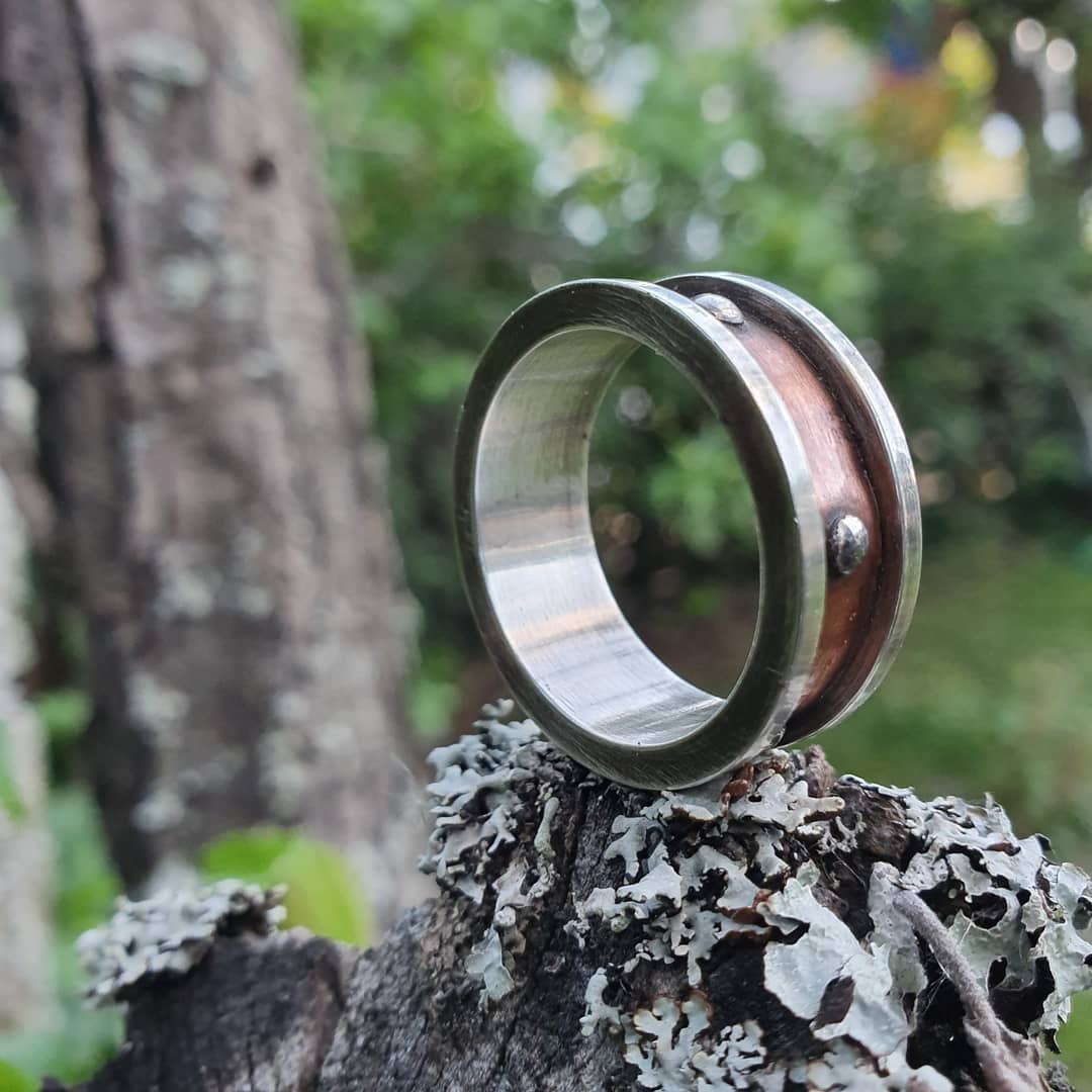 Jewelry maker inspecting a formed silver ring component on the workbench