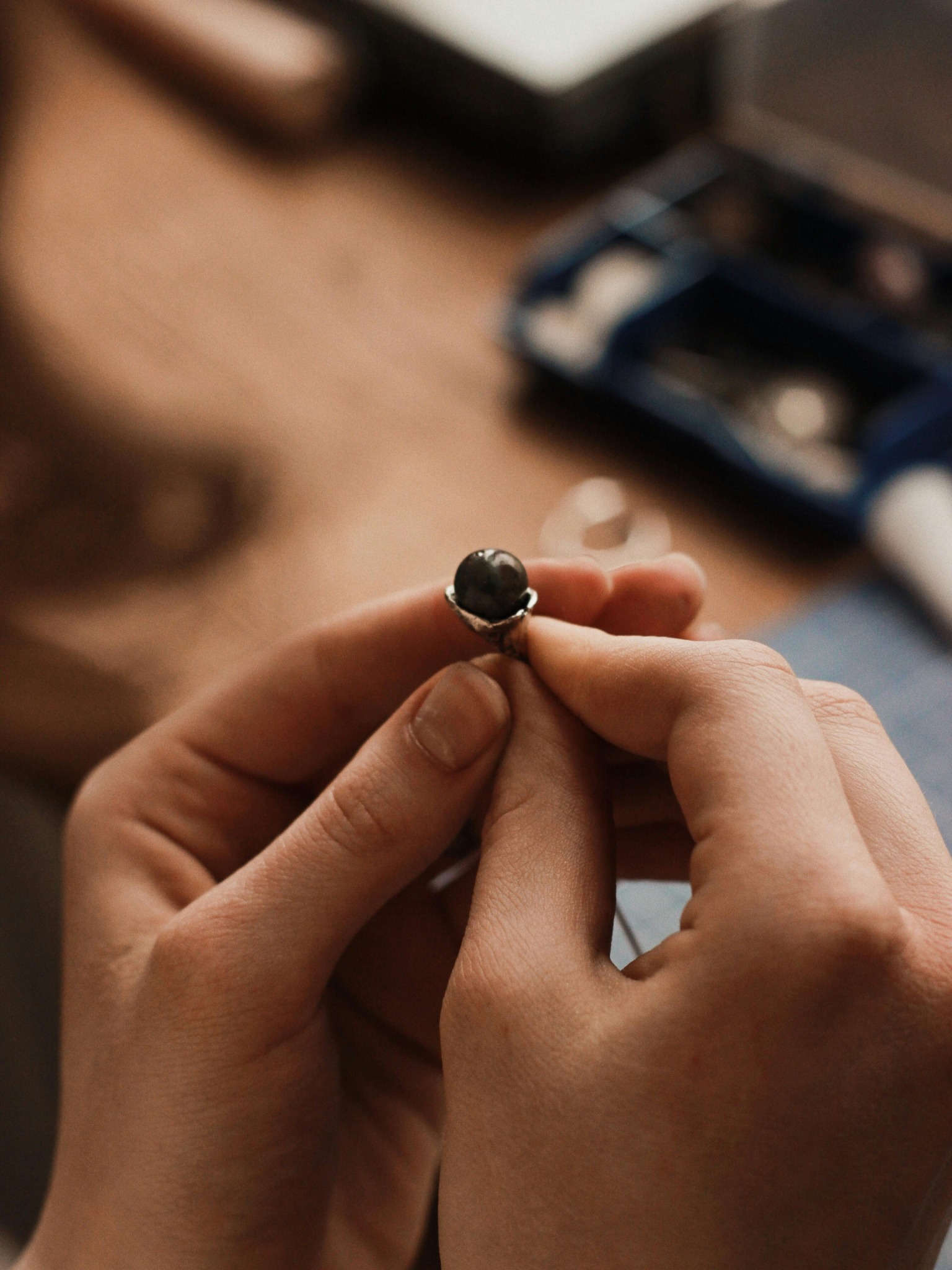 Hand inspecting a bezel set ring during careful stone setting work