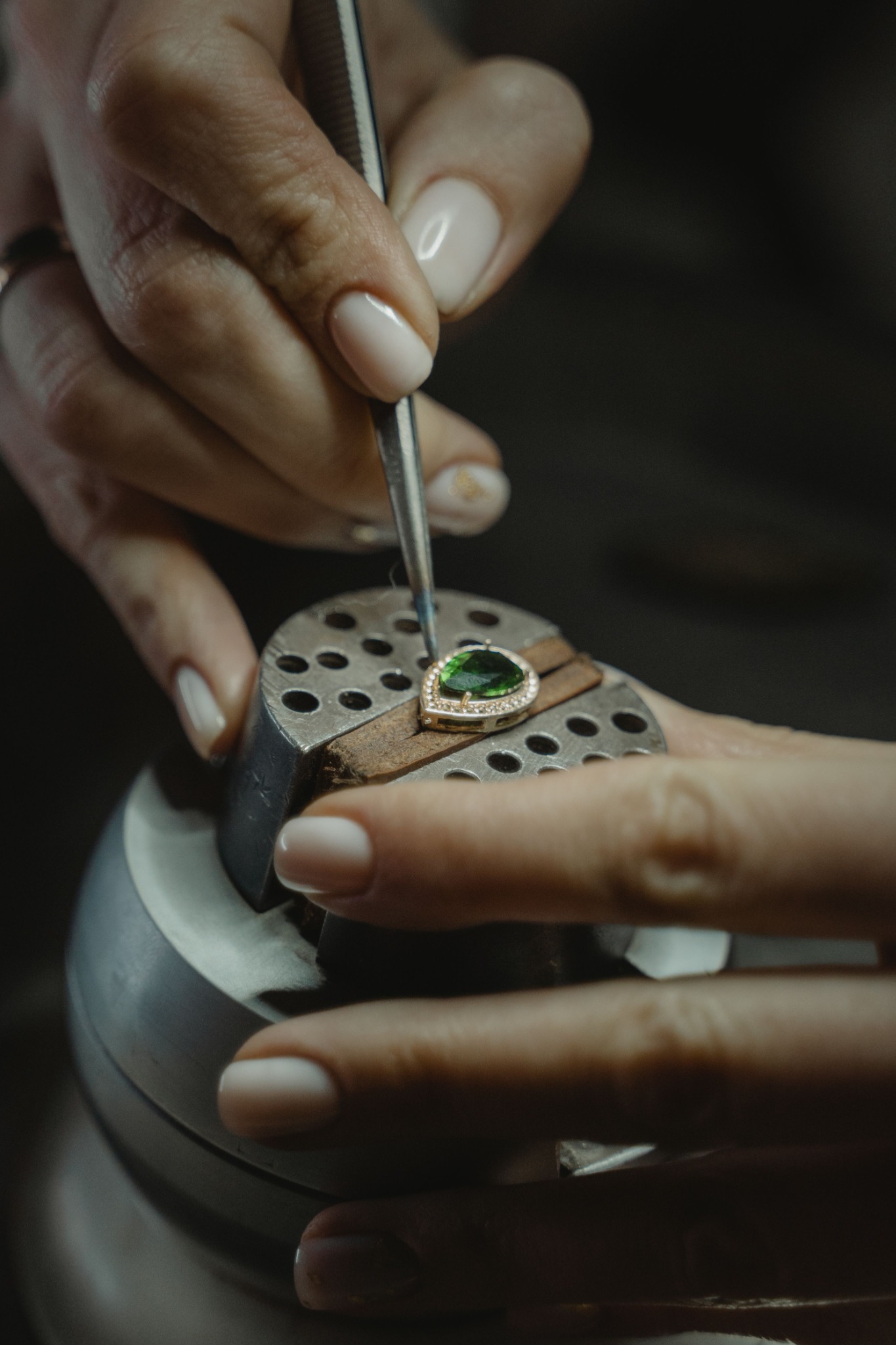Jewelry stone setting work with tweezers and a green stone held for precise setting
