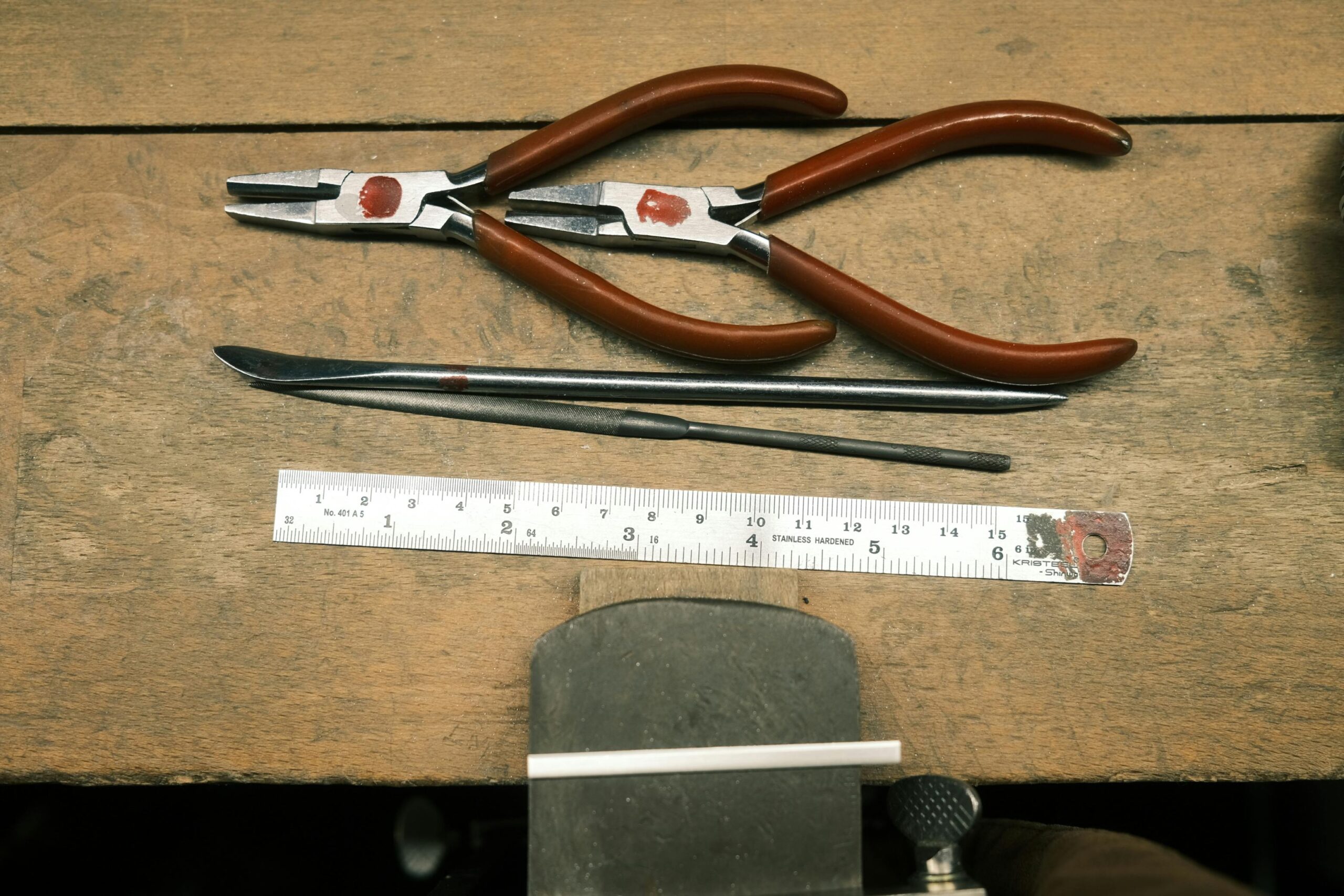Jewelry pliers, ruler and bench tools arranged on a work surface